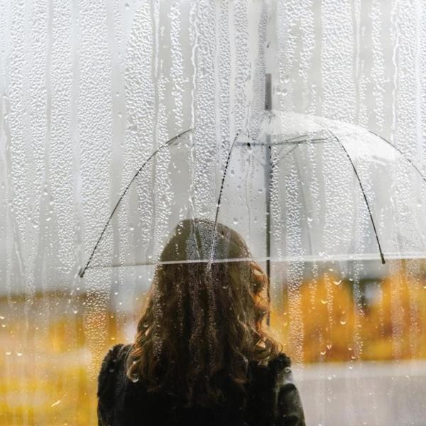 person standing under umbrella alone in the rain