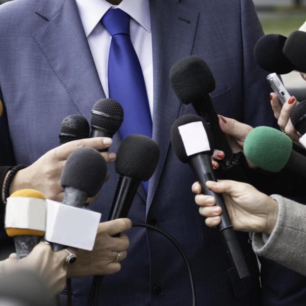 A stock photo of a press conference and reporters