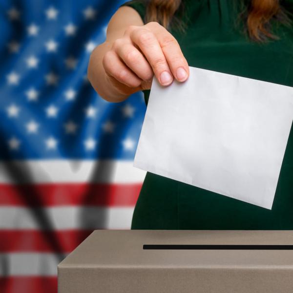 A person putting a ballot into a ballot box