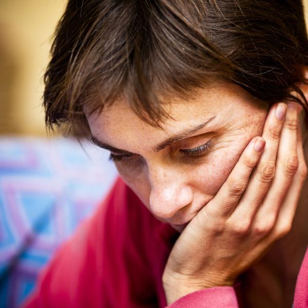 Woman holds head in hand | iStock photo credit to RapidEye