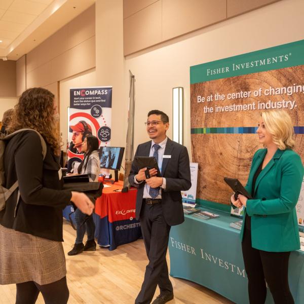 Student talking with employers at a career fair booth on campus