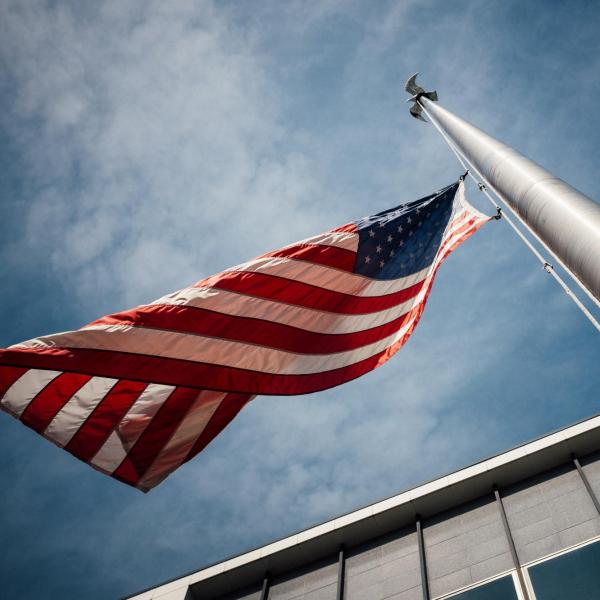 American flag flying with a dark, cloudy sky in the background