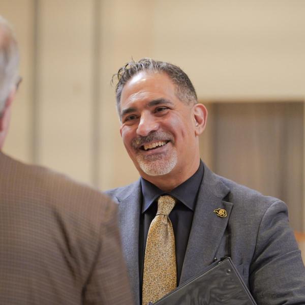 CU Boulder Chancellor Justin Schwartz interacts with a person standing before him.