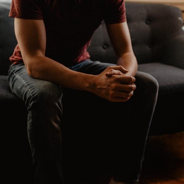 Person sitting on couch with hands folded on lap