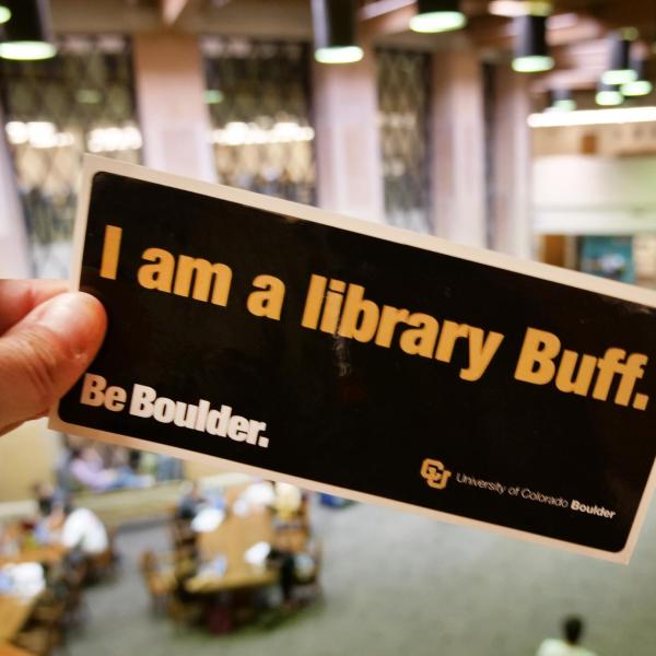 Person holding a 'I am a library Buff' bumper sticker