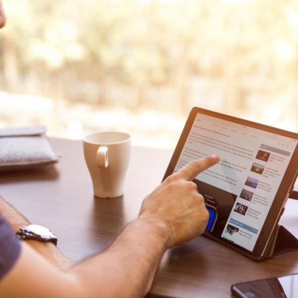 Person using tablet and drinking a cup of coffee
