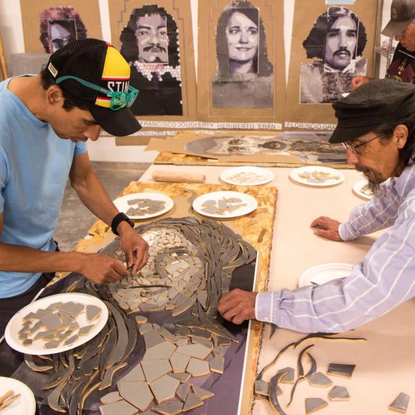 Artists work on part of a mosaic to commemorate 'Los Seis'