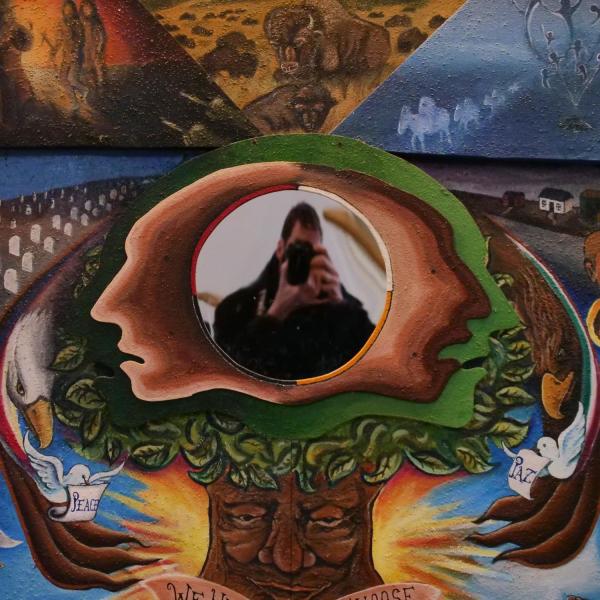CU Boulder photographer takes a self portrait on a mural in Norlin Library in 2018