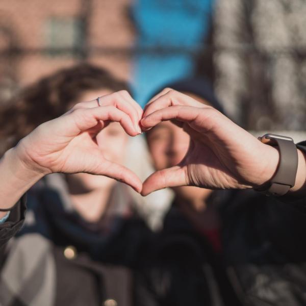 A couple forms a heart, each using one hand (Unsplash/Matt Nelson)