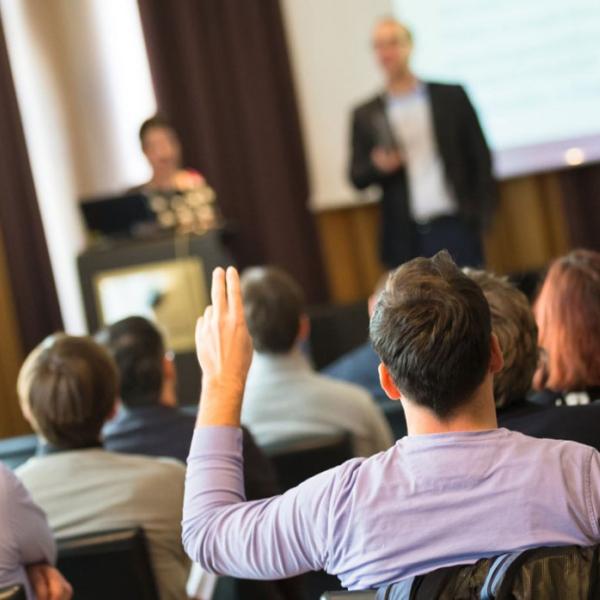 person raising their hand in a meeting room