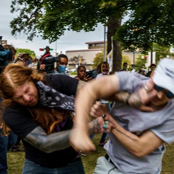 two men fighting in a public park while onlookers watch