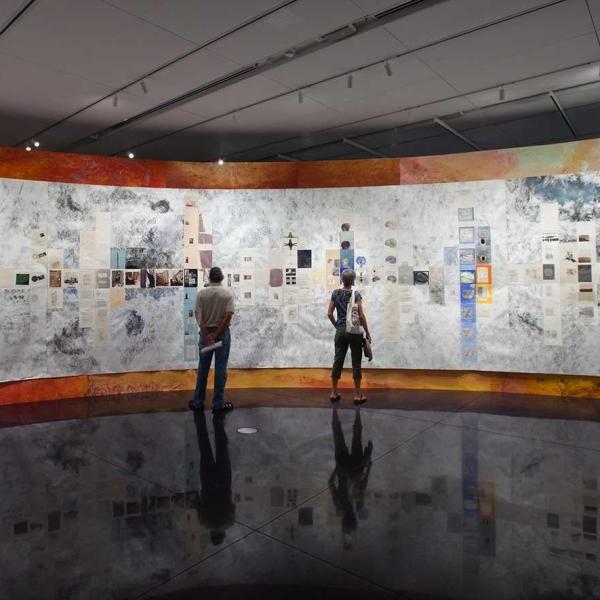 People stand, looking at an exhibit on a curved wall.