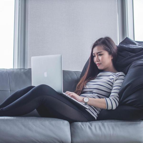 person works on laptop while sitting on couch