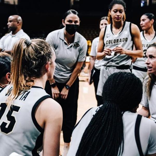 Members of the CU women's basketball team in a huddle on court.