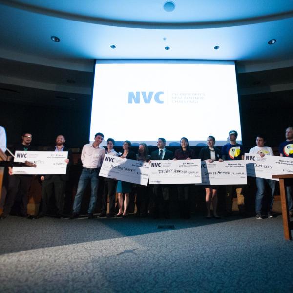 New Venture Challenge finalists pose with giant checks on stage