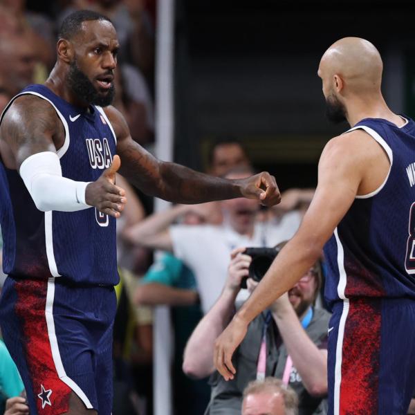 LeBron James and Derrick White interact on the basketball court, arms extended and facing each other.
