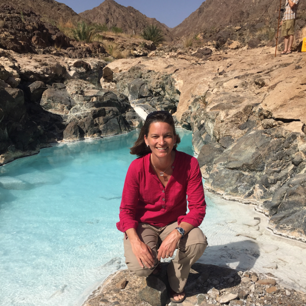 Alexis Templeton kneels on a rock in the middle of a spring