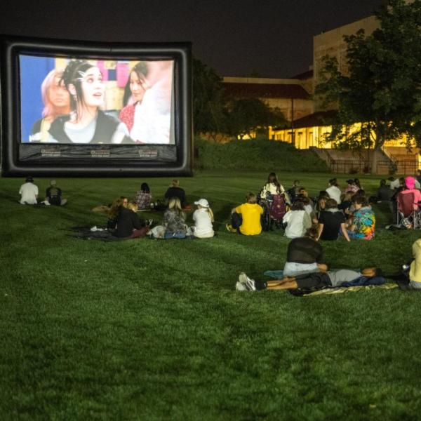Students watch movie on a lawn