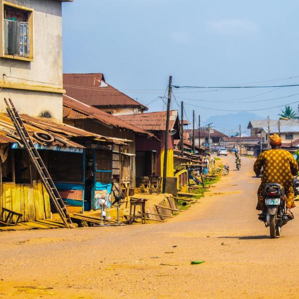 Man riding motorbike in village.