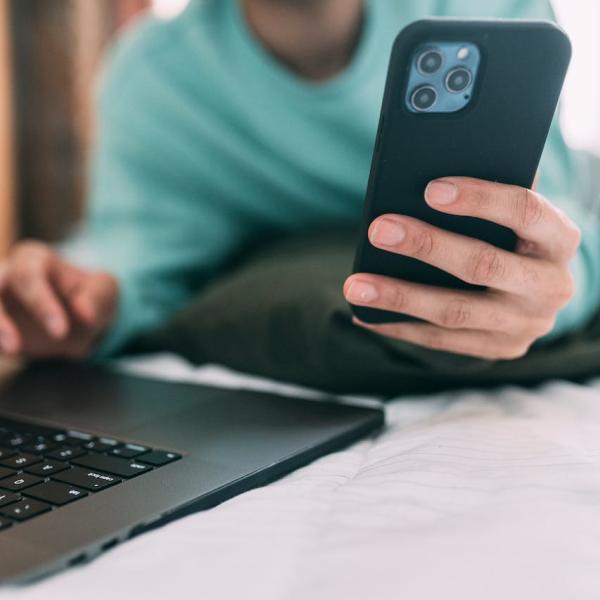 Person checking phone while using laptop