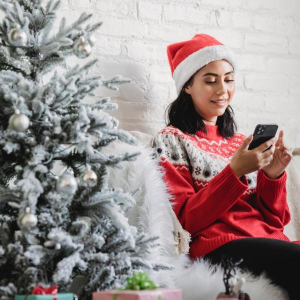 person on phone sitting next to Christmas tree