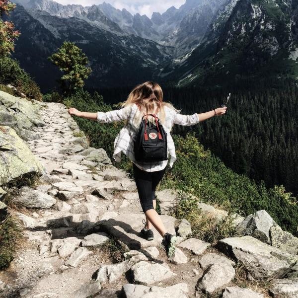 Girl skips down rocky path during hike in the mountains