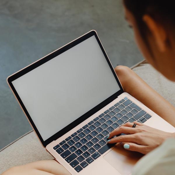 A person sits with a laptop in their lap. Photo by Karolina Grabowska from Pexels
