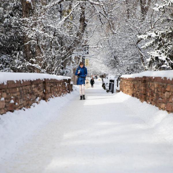students walking on a snowy bridge on campus