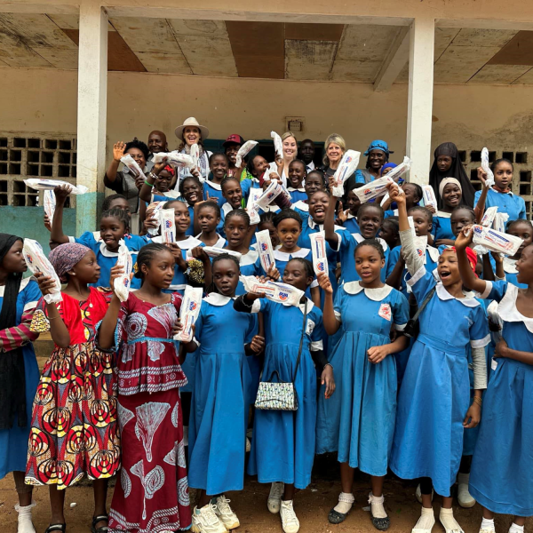 Women and girls in Cameroon excitedly holding biodegradable menstrual pads
