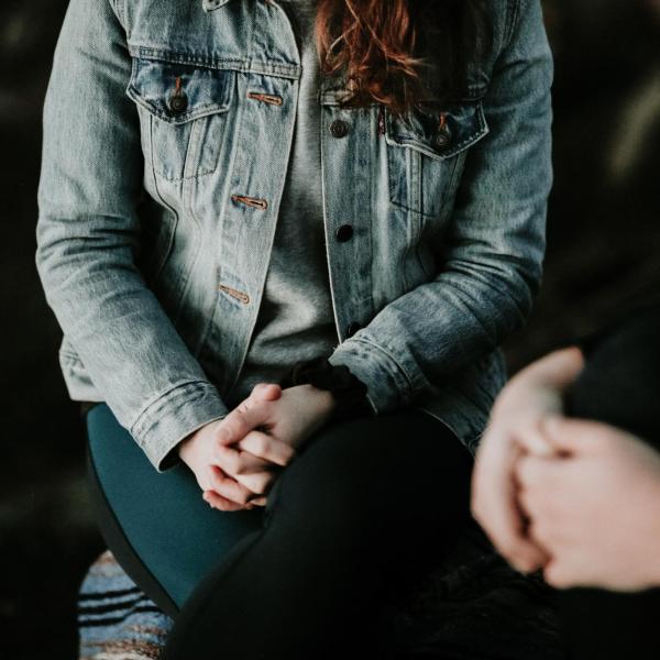 Young person sits with hands folded