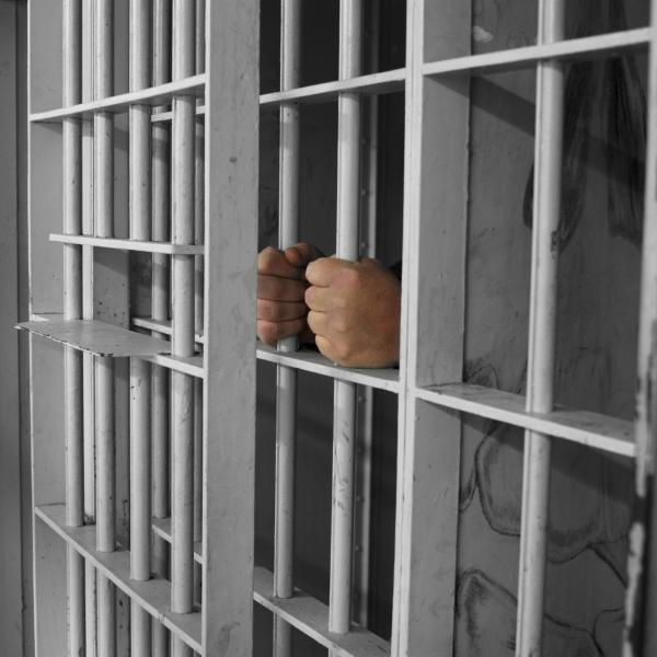 a man holding the bars of a prison cell