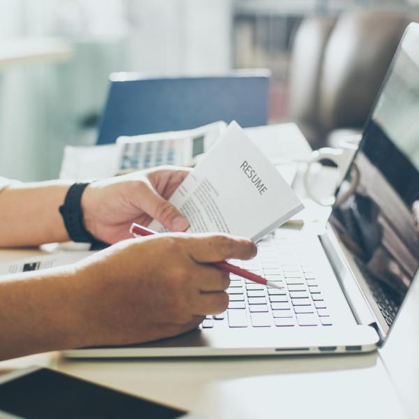 Person looking over resume while sitting at a computer