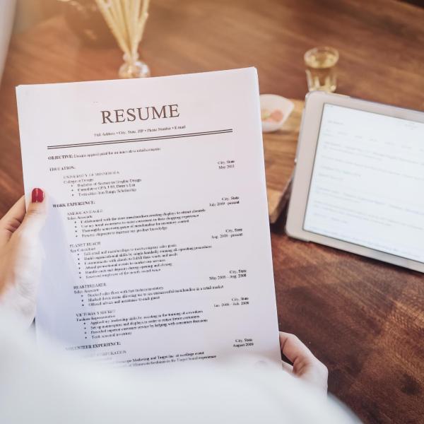 A women holding a sheet of paper that reads resume
