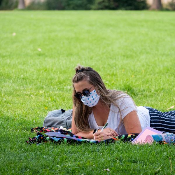 student lying in grass on campus
