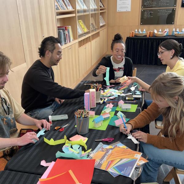 People sit around a table working with art supplies.
