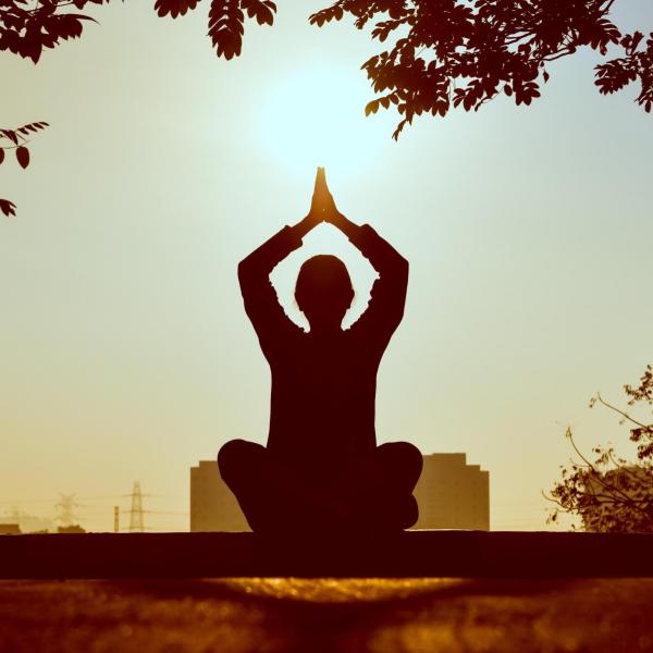 A person meditating outside at sunrise
