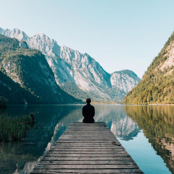 Person meditating by a lake