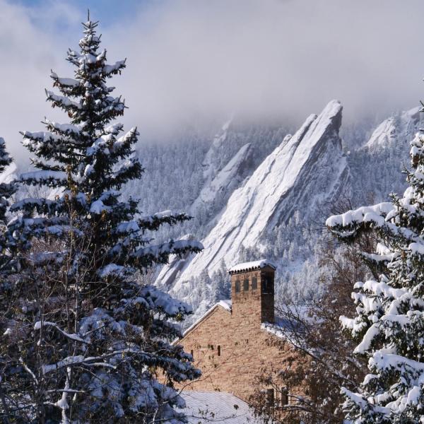 Top of a campus building with snowy Flatirons in the background
