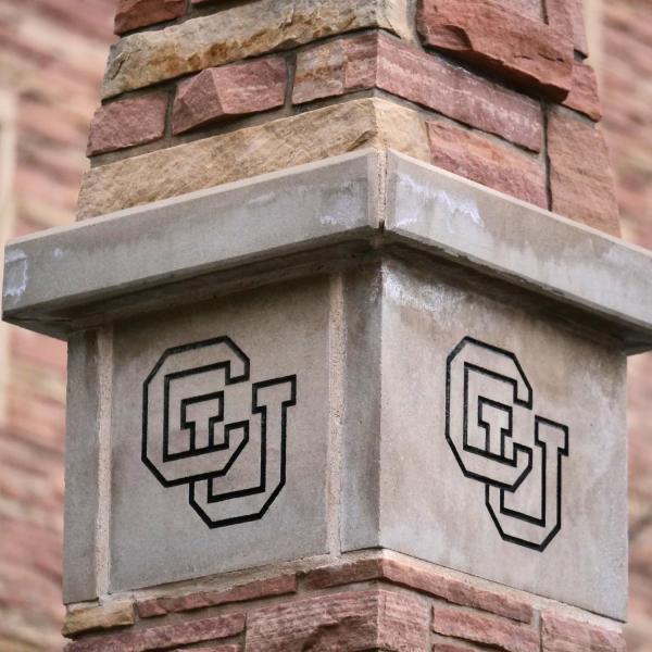 A stone column engraved with a CU symbol.