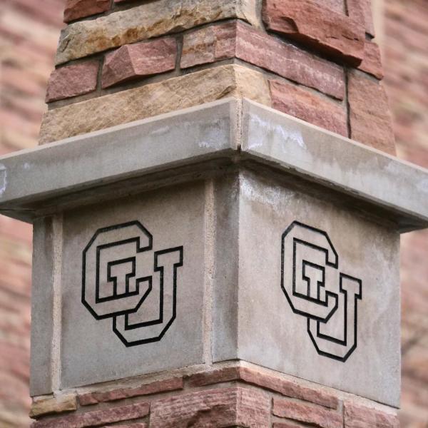 A stone column engraved with a CU symbol.
