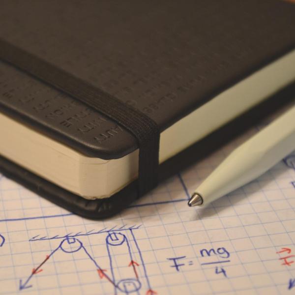 Notebook and graph paper with equations, sketches