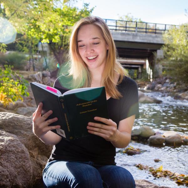 Woman reading book by creek