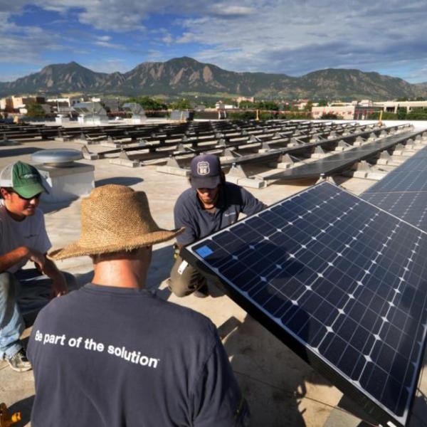 Workers install solar panels on CU Boulder rooftop