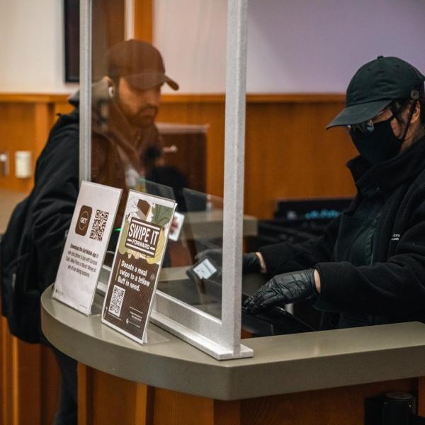 Dining center employee processes a student's meal card