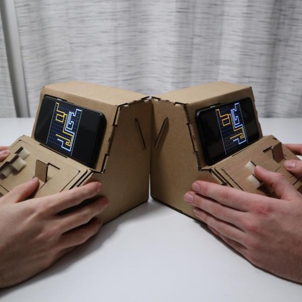 people playing with Tinycade cardboard controllers