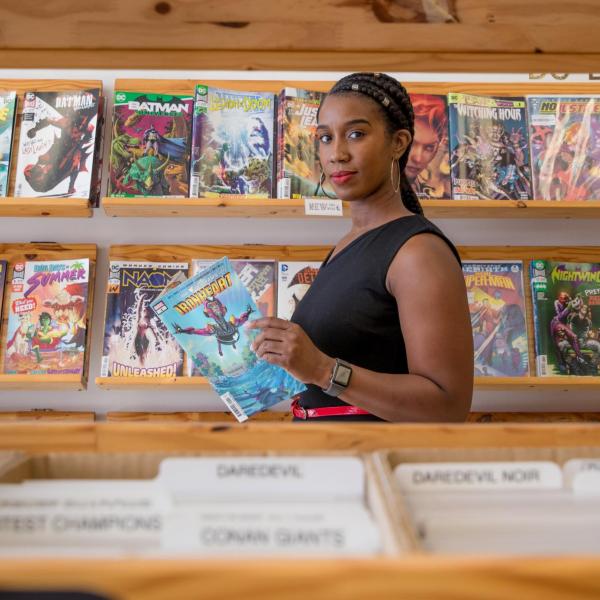 Stephanie Toliver in a comic book store reading an issue of "Ironheart"