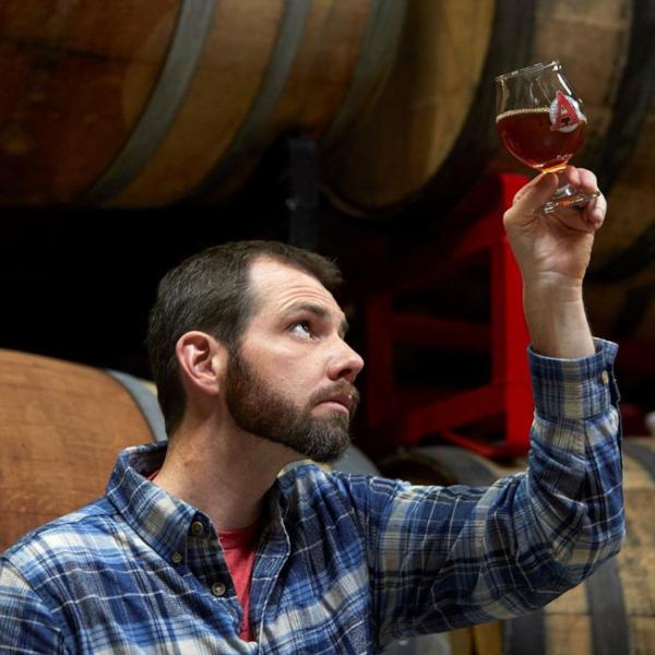 Travis Rupp holds a glass of beer up to the light