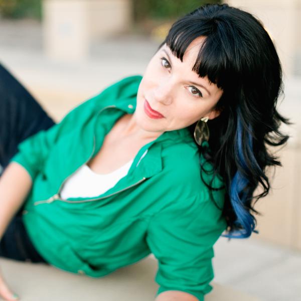 A woman in a green shirt looks into the camera