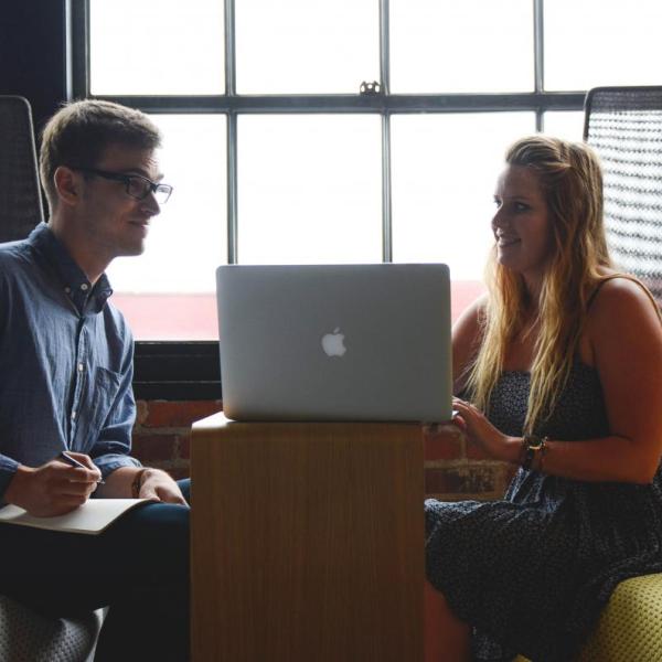 Two people talk over laptop computer
