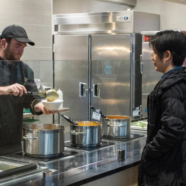 Dining services staff member serves food to a campus community member